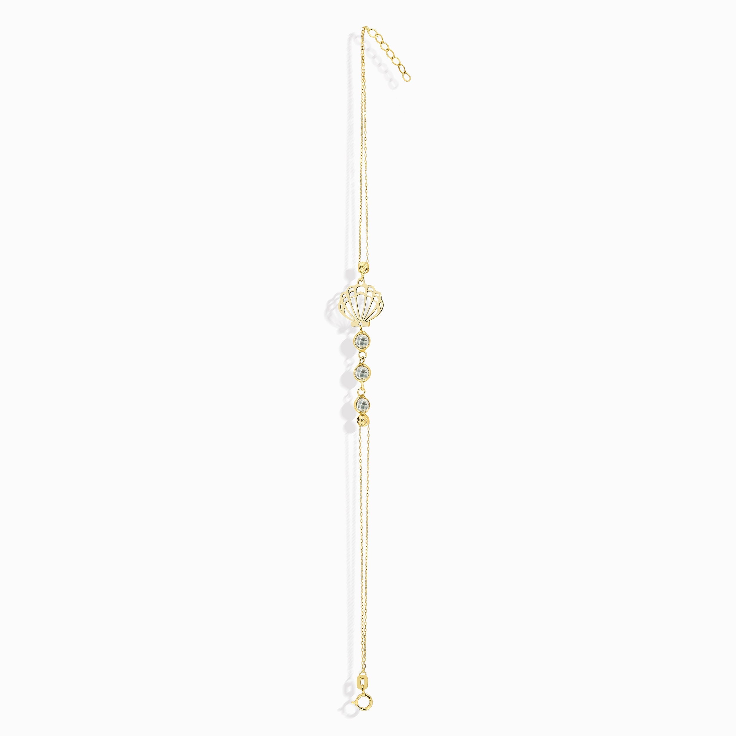 Elegant 14K gold bracelet with a cut-out seashell charm and faceted crystal beads, styled on rich emerald satin