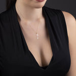 14K gold necklace with a key-shaped pendant featuring a four-leaf clover design, styled on magenta satin fabric.