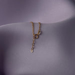 Elegant 14K gold bracelet with a cut-out seashell charm and faceted crystal beads, styled on rich emerald satin