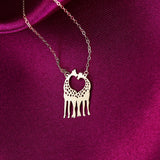 14K gold necklace with two giraffes forming a heart shape, laid on a magenta silk fabric background.