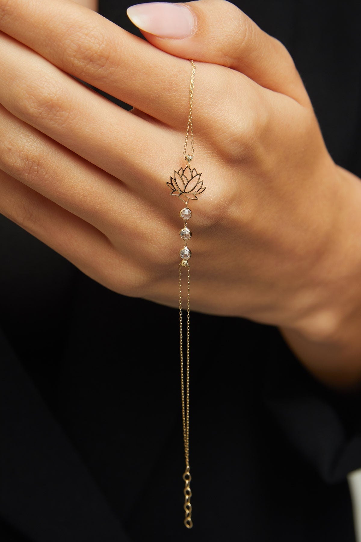 14K gold bracelet with lotus flower charm and faceted gemstone beads on emerald green satin background