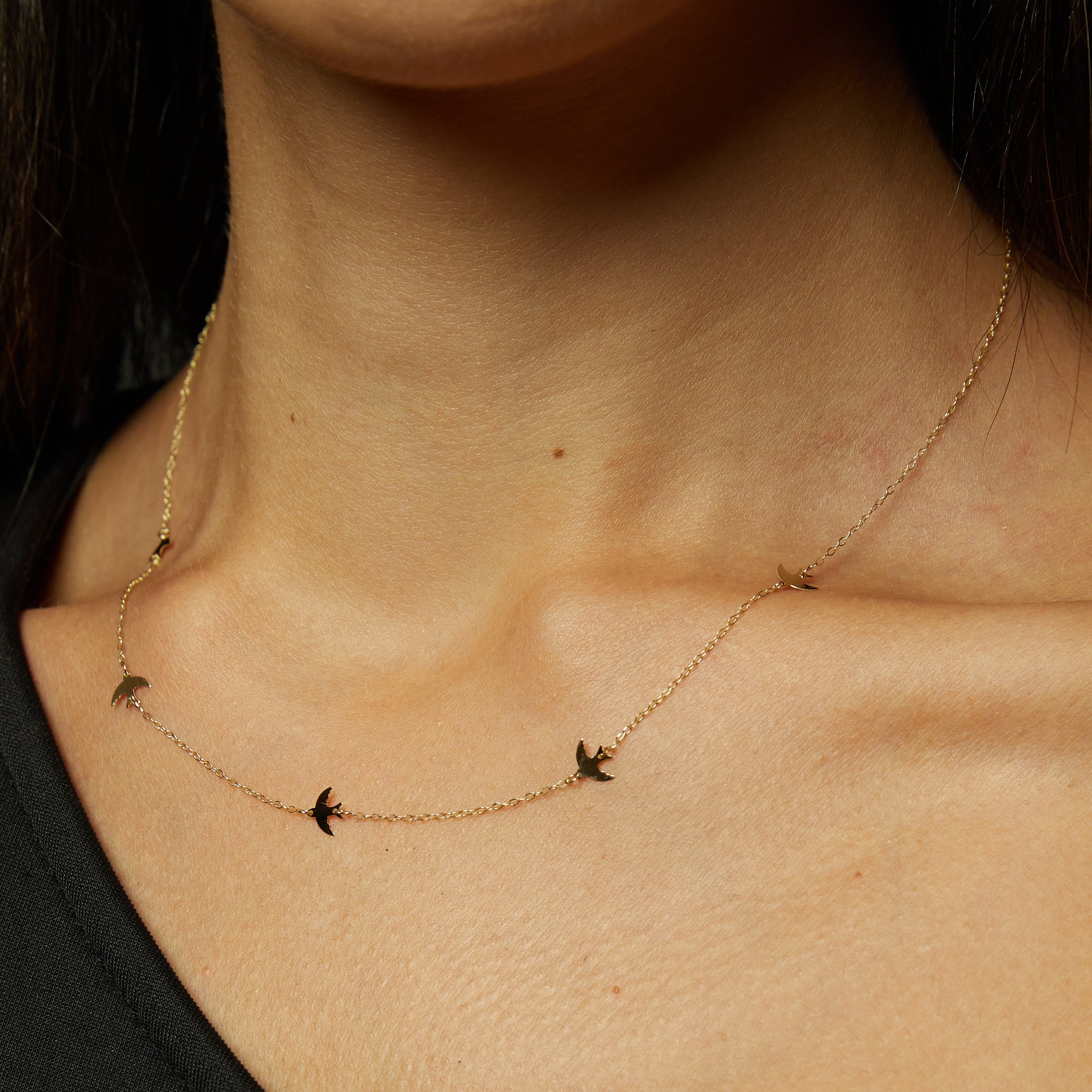 Minimalist 14K gold bracelet with flying bird charms on model’s