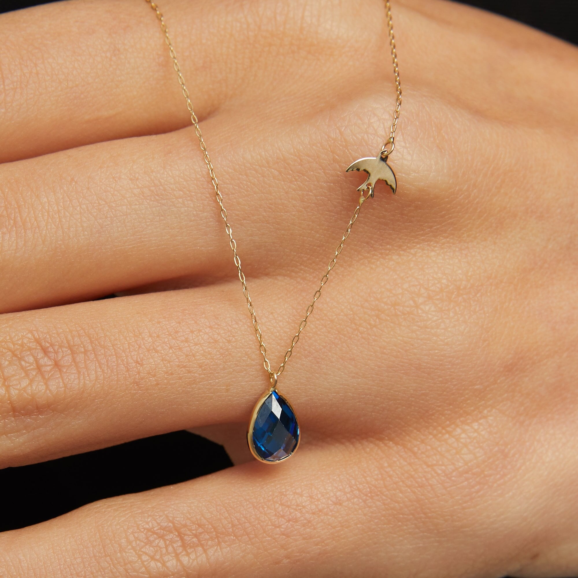 14K gold necklace with bird charm and blue sapphire teardrop pendant