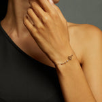 14K gold bracelet with lotus flower charm and faceted gemstone beads on emerald green satin background