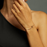 14K gold bracelet with lotus flower charm and faceted gemstone beads on emerald green satin background