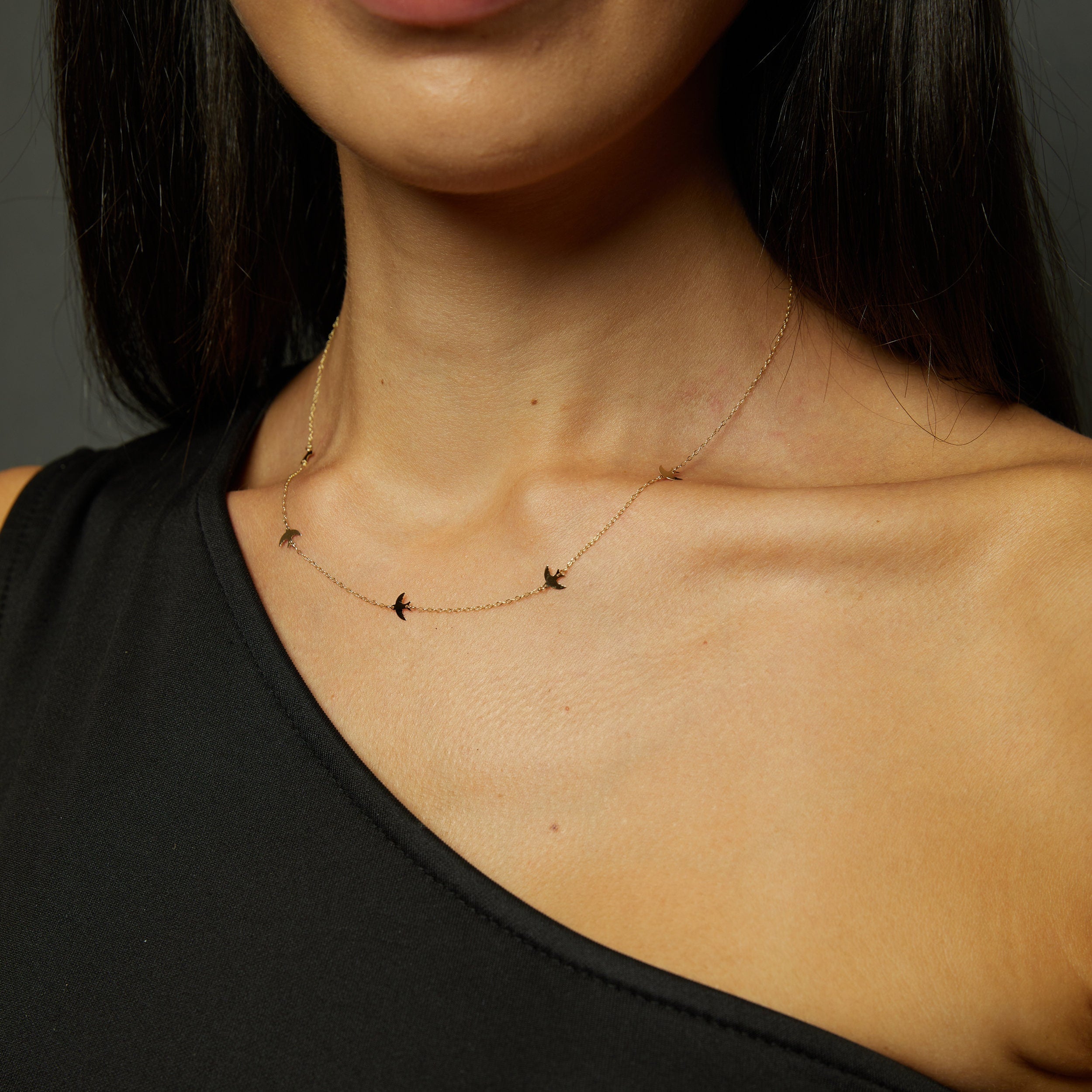 Minimalist 14K gold bracelet with flying bird charms on model’s