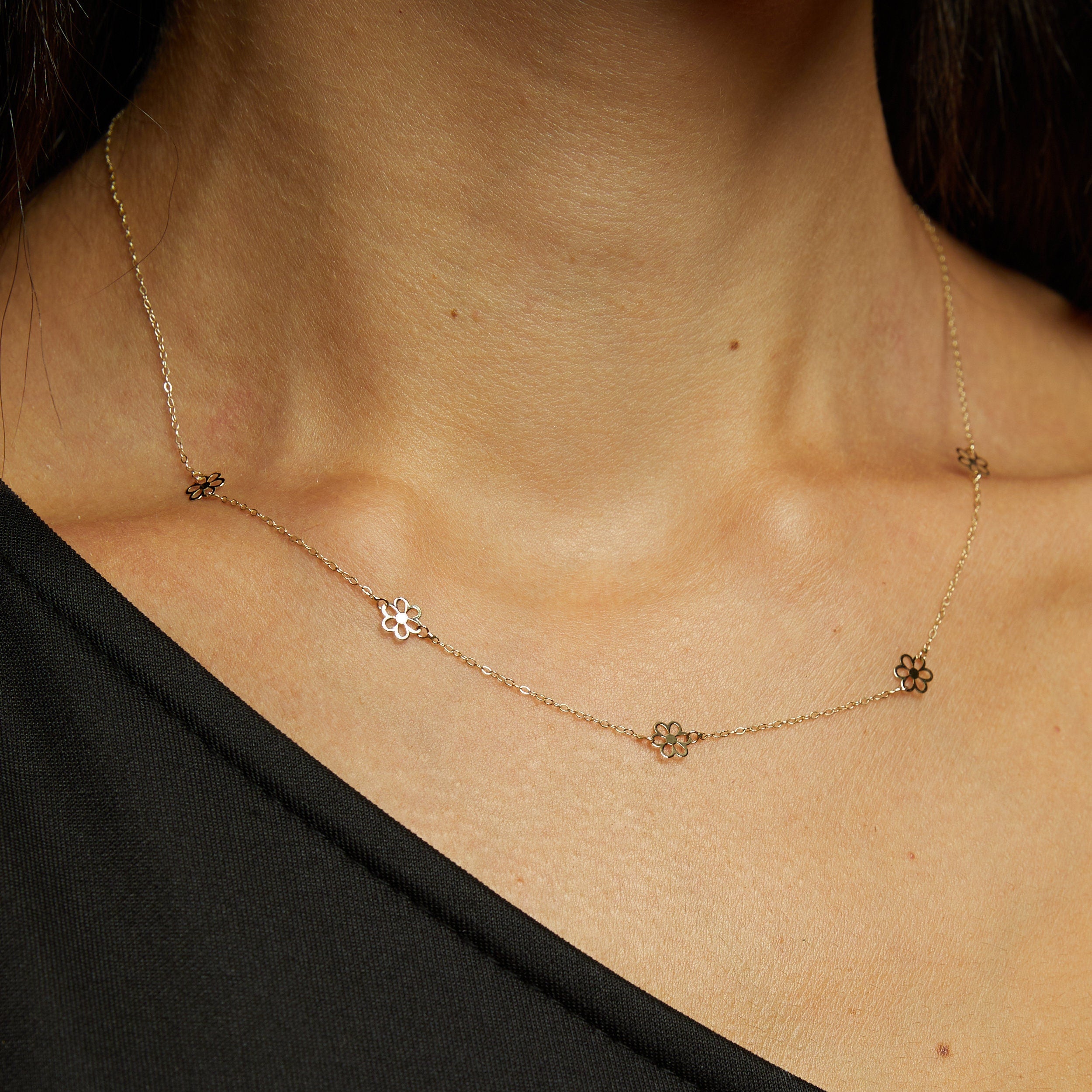 14K gold necklace featuring evenly spaced cut-out flower charms on a delicate chain