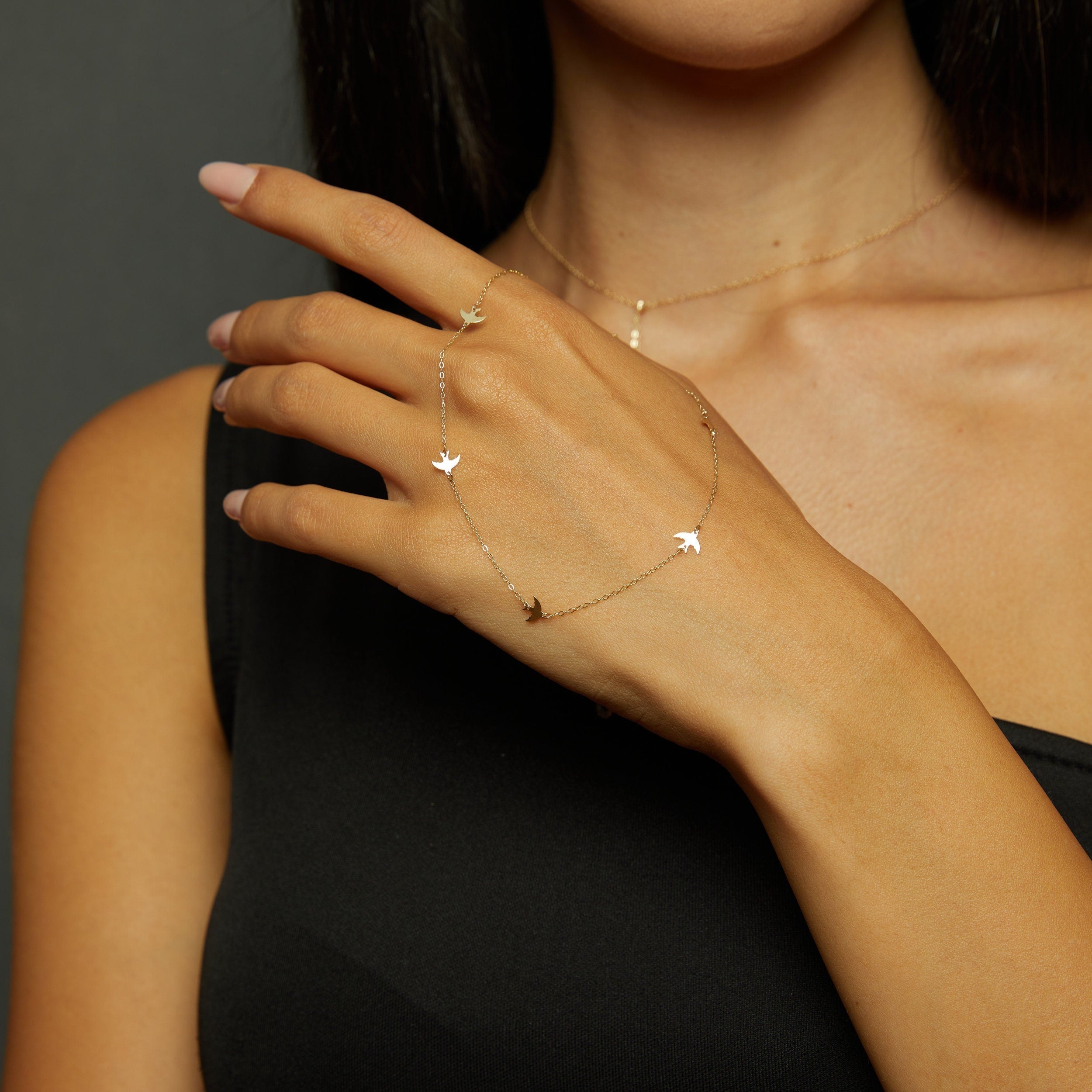 Minimalist 14K gold bracelet with flying bird charms on model’s