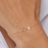 14K gold bracelet with a twisted circle centerpiece and two solid clover charms on a fine chain