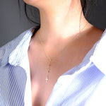 Close-up image of a 14K gold rosary-style necklace with a delicate cross pendant