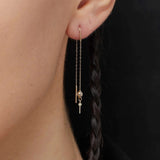 14K gold threader earrings with cross charm and clear crystal bead on model