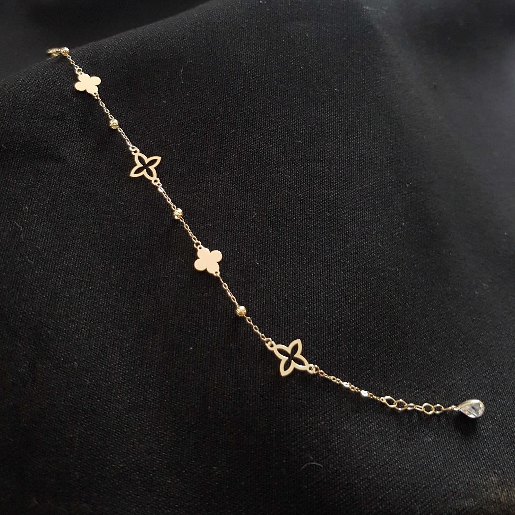 Elegant 14K gold bracelet featuring alternating solid and hollow clover charms with gold bead accents
