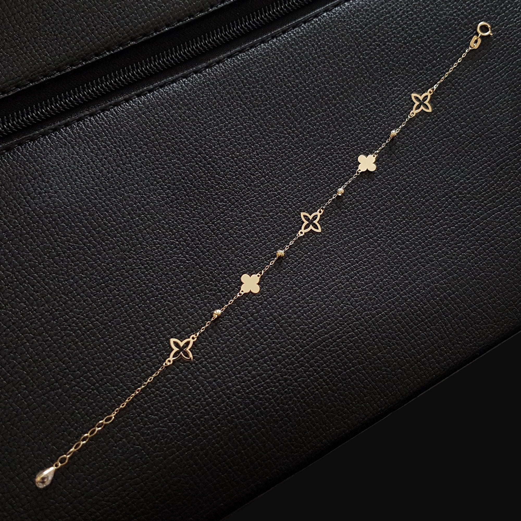 Elegant 14K gold bracelet featuring alternating solid and hollow clover charms with gold bead accents