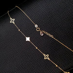 14K gold necklace with alternating solid and open clover charms on a delicate chain