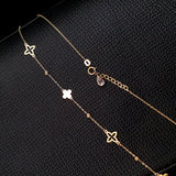 14K gold necklace with alternating solid and open clover charms on a delicate chain