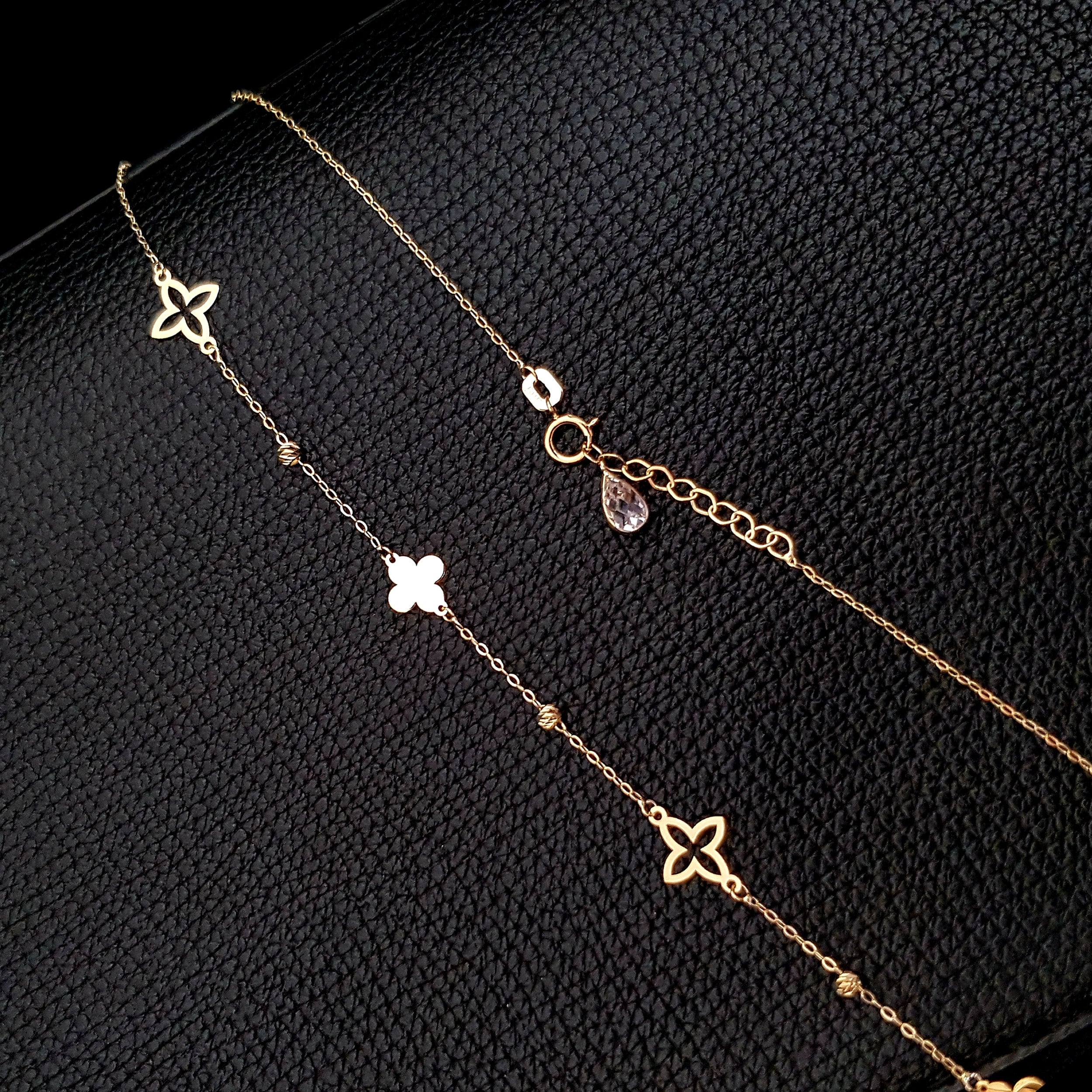 14K gold necklace with alternating solid and open clover charms on a delicate chain