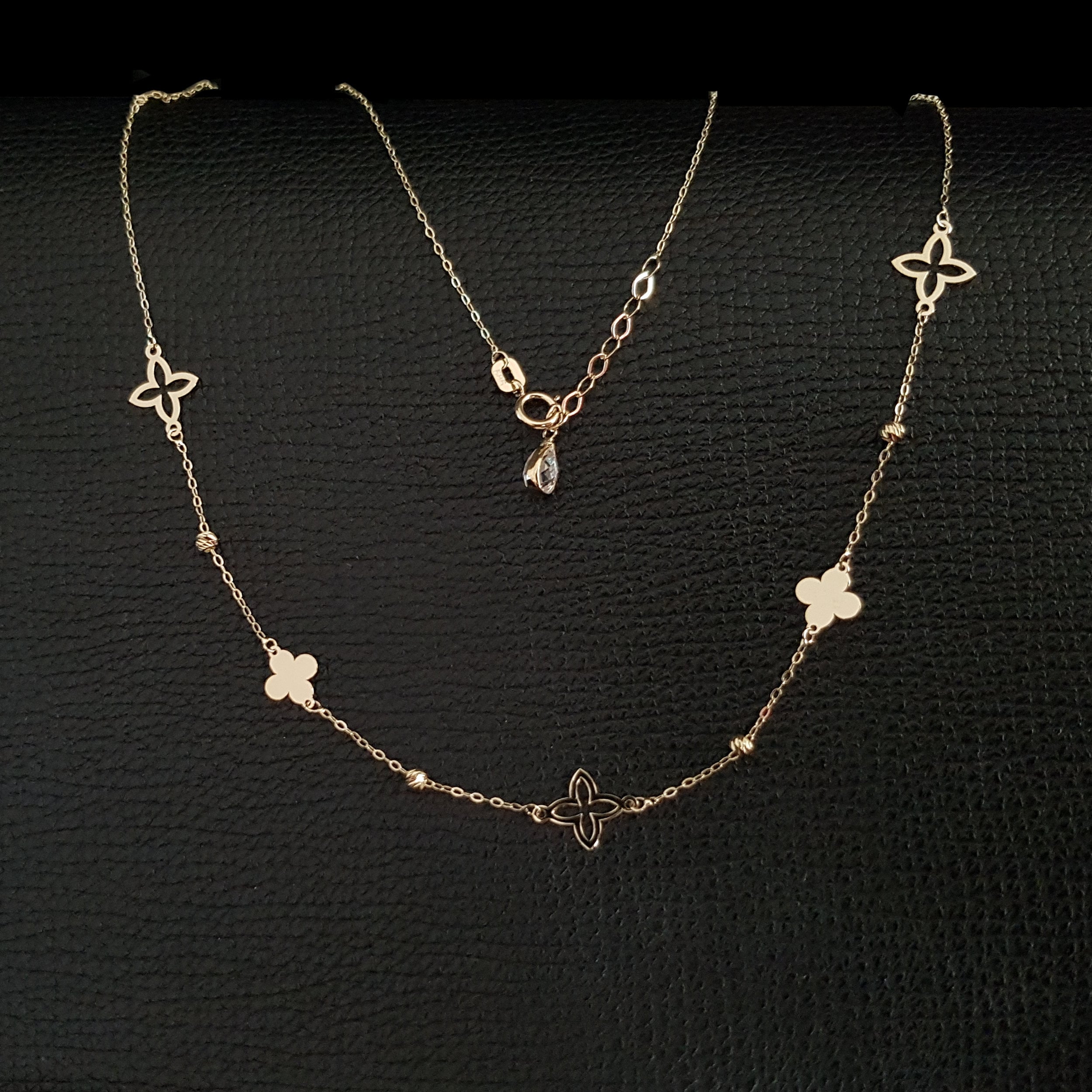 14K gold necklace with alternating solid and open clover charms on a delicate chain