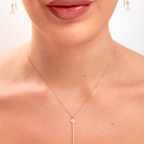 Close-up of woman wearing floral crystal drop necklace and gold initial threader earrings, featuring the letter “A”

