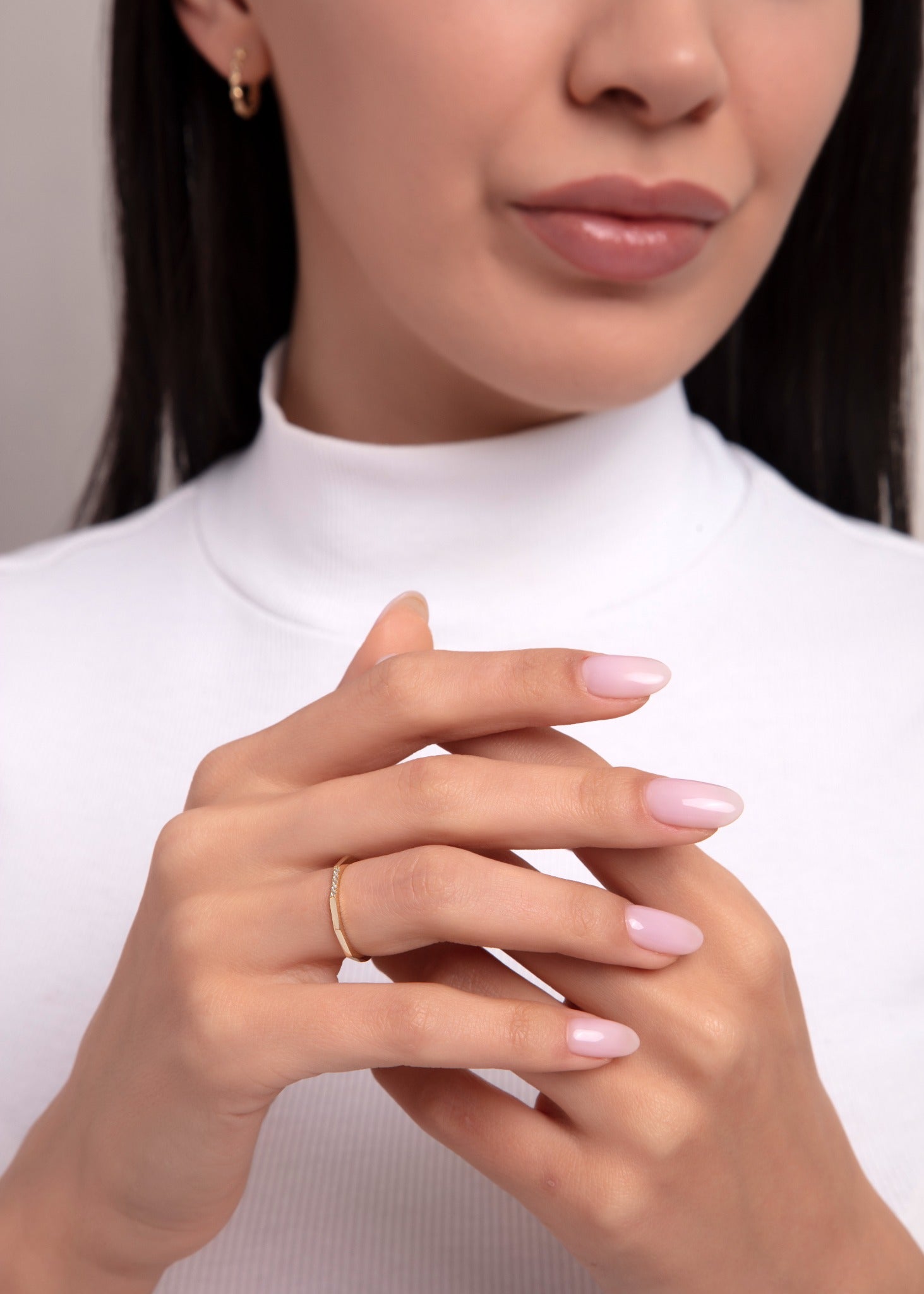woman wearing a minimalist gold ring with small diamonds, close-up hand pose

